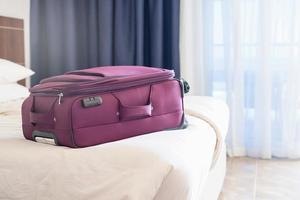 valise emballée violette sur le lit dans la chambre d'hôtel photo