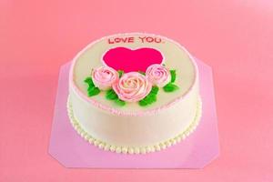 crème au beurre de roses roses décorées oo gâteau d'étang à la vanille sur fond rose avec espace de copie servi dans la fête d'anniversaire et le mariage. délicieuse boulangerie sucrée pour quelqu'un que vous aimez. photo
