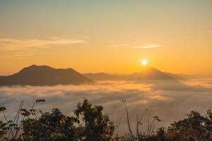 le brouillard de mer et le lever du soleil doré couvrent la zone au sommet de la colline doi phu thok, chiang khan, loei, thaïlande avec fond de lever de soleil en hiver. photo