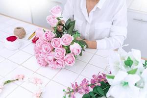 jeune femme propriétaire d'entreprise fleuriste fabriquant ou organisant des fleurs artificielles gilet dans sa boutique, artisanat et concept fait à la main photo