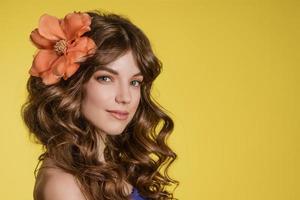 portrait jeune femme sur fond jaune avec une fleur dans les cheveux photo