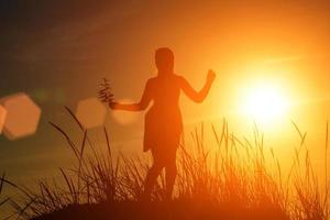 silhouette d'une fille heureuse au soleil couchant photo