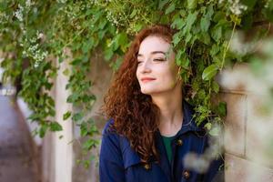 belle jeune femme aux cheveux rouges et aux taches de rousseur sur fond de mur photo