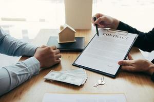 les agents utilisent des stylos pointant vers les contrats d'assurance et sont expliqués aux clients au bureau. photo