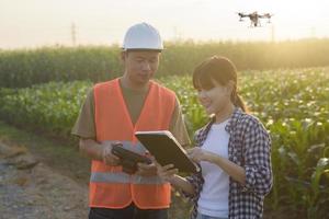 un ingénieur masculin fournit une consultation et donne des instructions à un agriculteur intelligent avec un drone pulvérisant des engrais et des pesticides sur les terres agricoles, des innovations de haute technologie et une agriculture intelligente photo