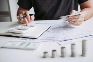 l'homme utilise des calculatrices et des documents qui calculent les dépenses au bureau à domicile. photo