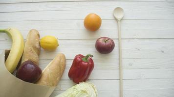 sac en papier plein de produits alimentaires avec petit cahier vierge sur table en bois, vue de dessus photo