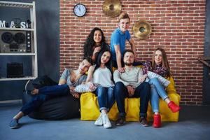 portrait de groupe de garçons et de filles multiethniques avec des vêtements colorés à la mode tenant un ami posant sur un mur de briques, des gens de style urbain s'amusant, des concepts sur le mode de vie de la jeunesse photo