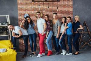 portrait de groupe de garçons et de filles multiethniques avec des vêtements colorés à la mode tenant un ami posant sur un mur de briques, des gens de style urbain s'amusant, des concepts sur le mode de vie de la jeunesse photo