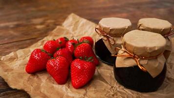 confiture de fraises dans le bocal en verre avec des baies fraîches sur fond de bois photo