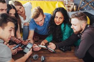 vue de dessus cercle de mains à l'aide d'un téléphone dans un café - amis multiraciaux scène intérieure mobile dépendante d'en haut - personnes connectées au wifi lors d'une réunion de table de bar - concept de travail d'équipe photo