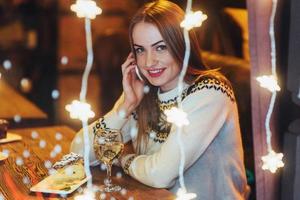 belle jeune femme assise dans un café, buvant du vin. noël, nouvel an, saint valentin, concept de vacances d'hiver photo