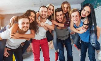 portrait de groupe de garçons et de filles multiethniques avec des vêtements colorés à la mode tenant un ami posant sur un mur de briques, des gens de style urbain s'amusant, des concepts sur le mode de vie de la jeunesse photo