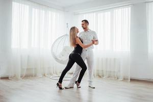 jeune couple dansant la musique latine bachata, merengue, salsa. deux poses d'élégance sur la salle blanche photo