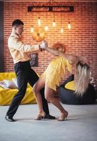 jeune couple dansant de la musique latine. bachata, mérengue, salsa. deux poses d'élégance sur un café aux murs de briques photo