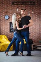 jeune couple dansant la musique latine bachata, merengue, salsa. deux poses d'élégance sur un café aux murs de briques photo