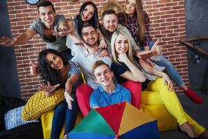 portrait de groupe de garçons et de filles multiethniques avec des vêtements colorés à la mode tenant un ami posant sur un mur de briques, des gens de style urbain s'amusant, des concepts sur le mode de vie de la jeunesse photo