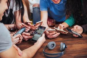 vue de dessus cercle de mains à l'aide d'un téléphone dans un café - amis multiraciaux scène intérieure mobile dépendante d'en haut - personnes connectées au wifi lors d'une réunion de table de bar - concept de travail d'équipe photo