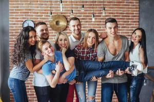 portrait de groupe de garçons et de filles multiethniques avec des vêtements colorés à la mode tenant un ami posant sur un mur de briques, des gens de style urbain s'amusant, des concepts sur le mode de vie de la jeunesse photo