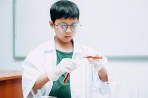 étudiant garçon asiatique avec des tubes à essai étudiant la chimie au laboratoire de l'école, versant du liquide. journée nationale de la science, journée mondiale de la science