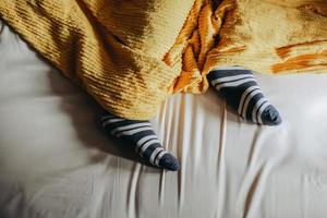 pieds dans des chaussettes chaudes sous les couvertures sur le lit photo
