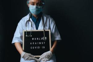 femme médecin avec citation sur le tableau des lettres dit monde contre covid 19 isolé sur fond noir. campagne contre le coronavirus avec espace de copie