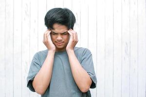 jeune asiatique souffrant de maux de tête et stressé à cause de la douleur et de la migraine. mains sur la tête photo