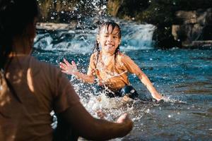 petite fille asiatique jouant dans le ruisseau de la forêt avec sa sœur. loisirs actifs avec les enfants sur la rivière en été. photo