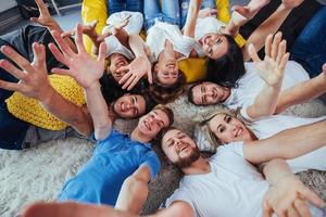 groupe de beaux jeunes gens faisant du selfie allongé sur le sol, meilleurs amis filles et garçons s'amusant ensemble, posant un concept de mode de vie émotionnel photo