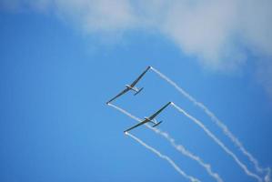 deux avions glissent avec du brouillard dans le ciel bleu lors d'un spectacle aérien photo