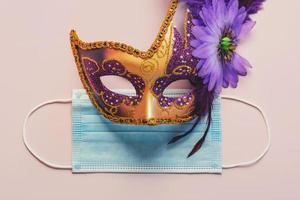 concept de carnaval pendant covid-19. masque de carnaval vénitien avec masque chirurgical de protection. concept de célébration de carnaval photo