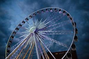 grande grande roue lumineuse devant un ciel dramatique bleu foncé photo