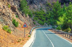 route sinueuse asphaltée dans la chaîne de montagnes de troodos avec clôture en bordure de route et arbres photo