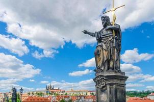 statue de saint jean le baptiste sur le pont charles karluv most sur la rivière vltava avec le château de prague photo