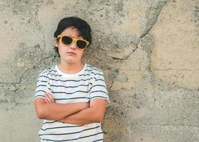 garçon rebelle avec des lunettes de soleil à côté d'un mur photo