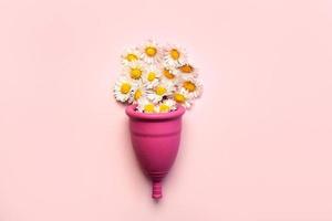 coupe menstruelle en silicone avec des fleurs de marguerite blanche.concept féminin d'hygiène gynécologique alternative intime photo