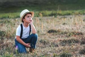 enfant réfléchi avec t-shirt blanc et chapeau photo