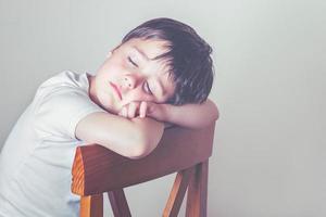 enfant triste assis sur une chaise photo