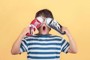 enfant drôle qui couvre les yeux avec des baskets photo