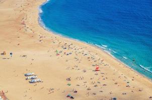 haut vue aérienne de la plage de sable avec des touristes prenant un bain de soleil et de l'eau turquoise azur de l'océan atlantique, praia da nazare photo