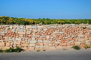 mur orange jaune de brique de pierre le long de la rue d'asphalte, malte