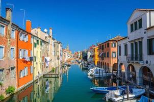 paysage urbain de chioggia avec veine étroite du canal d'eau avec bateaux multicolores amarrés photo