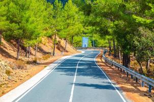 route sinueuse asphaltée dans la chaîne de montagnes de troodos avec clôture en bordure de route et arbres photo