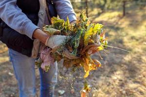 jeune garçon ramasse les feuilles mortes en automne photo