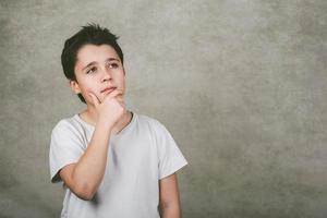 enfant réfléchi sur fond gris photo