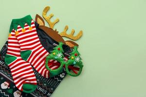 joyeux Noël. vue de dessus du chandail de noël avec des chaussettes de noël, des bois de cerf de jouet de noël lumineux et des lunettes amusantes. fond de concept de noël photo