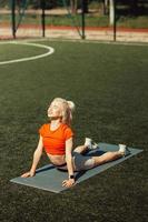 belle blonde faisant des étirements sur la pelouse d'un terrain de football photo