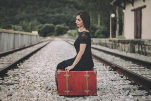 jeune femme assise sur une valise à la gare photo