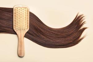 brosse à cheveux avec serrure de cheveux bruns féminins. salon de coiffure et concept de coiffures photo