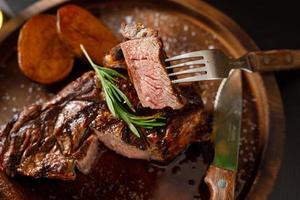 steak mi-saignant sur côte de veau à l'os avec pomme de terre sur une assiette en bois photo